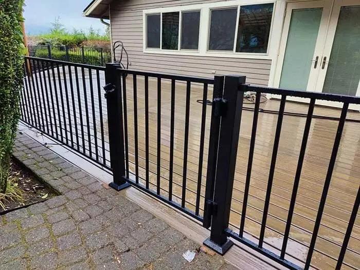 Black gate on a deck to patio border made from aluminum picket deck railing material.